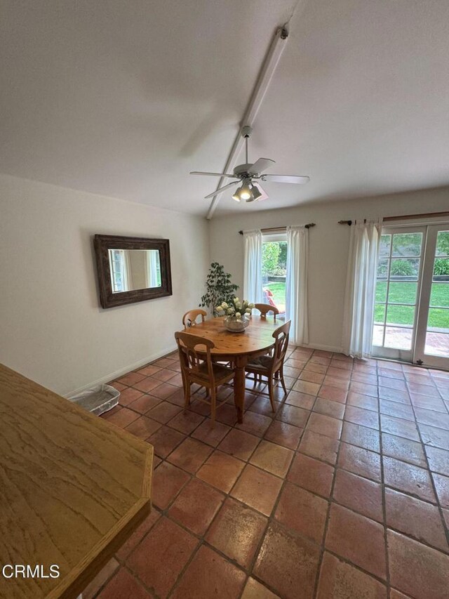 tiled dining space with ceiling fan and baseboards