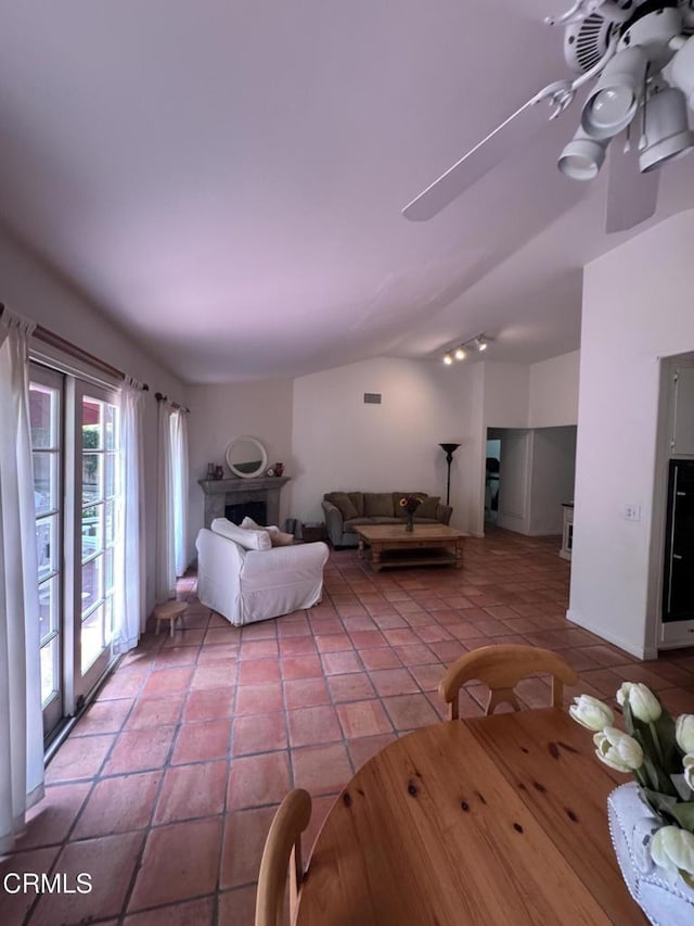 living area featuring ceiling fan, light tile patterned floors, and lofted ceiling