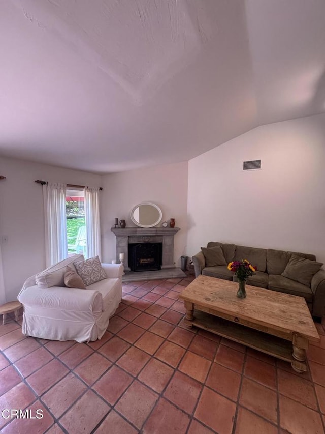 living area featuring a fireplace with raised hearth, lofted ceiling, and light tile patterned floors