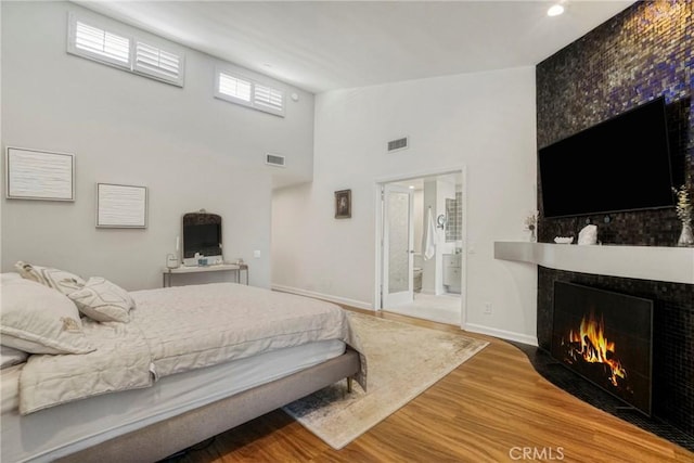 2311 Roscomare Rd Unit 16, Los Angeles, CA 90077 - bedroom with a fireplace with flush hearth, wood finished floors, a towering ceiling, and connected bathroom