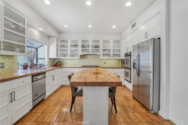 2311 Roscomare Rd Unit 16, Los Angeles, CA 90077 - kitchen featuring appliances with stainless steel finishes, wooden counters, white cabinetry, a breakfast bar, and glass insert cabinets