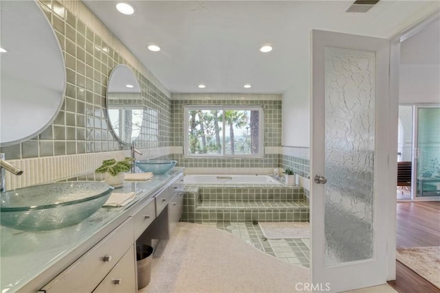 2311 Roscomare Rd Unit 16, Los Angeles, CA 90077 - bathroom featuring tile walls, a bath, double vanity, and recessed lighting