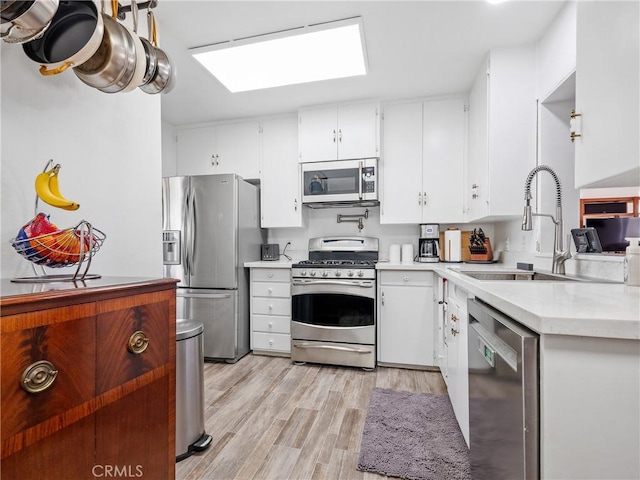 14060 Osage Rd, Apple Valley, CA 92307 - kitchen with appliances with stainless steel finishes, a sink, light countertops, light wood finished floors, and white cabinets
