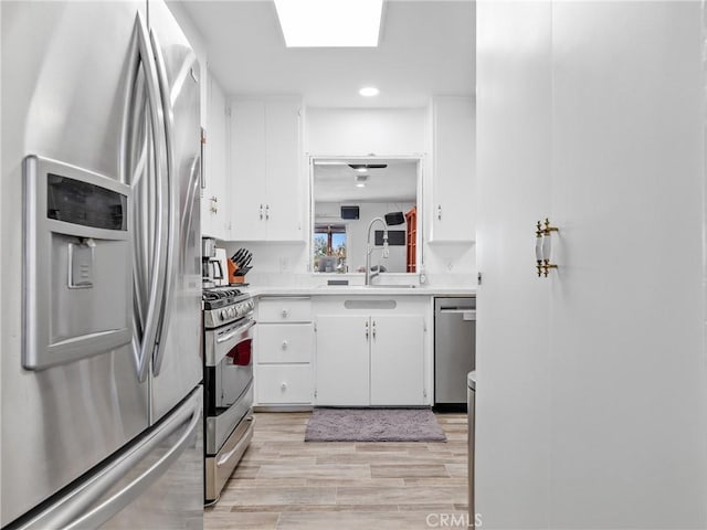 14060 Osage Rd, Apple Valley, CA 92307 - kitchen with stainless steel appliances, a sink, light countertops, light wood-type flooring, and white cabinetry