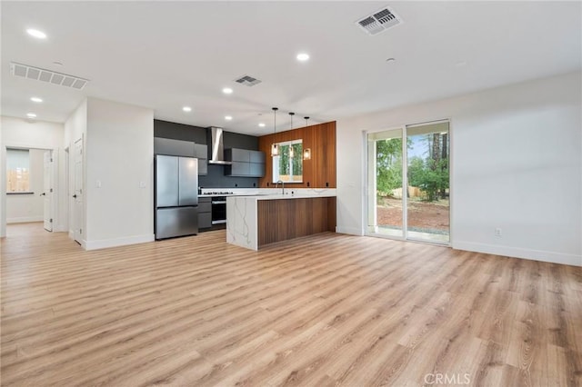 6296 Diamond Ave, Paradise, CA 95969 - kitchen featuring freestanding refrigerator, wall chimney range hood, light countertops, light wood-style flooring, and recessed lighting
