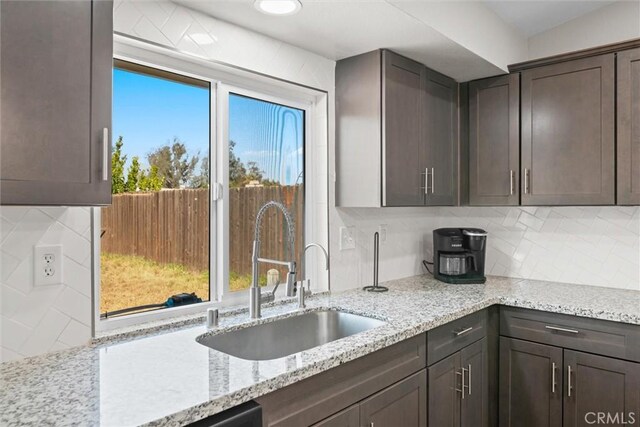19018 Tule Way, Lake Elsinore, CA 92530 - kitchen with a sink, decorative backsplash, dark brown cabinetry, and light stone countertops