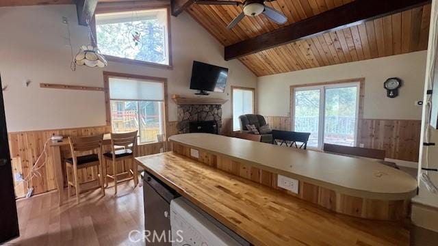 33421 Wild Rose Dr, Green Valley Lake, CA 92341 - dining area with wooden walls, wainscoting, a fireplace, beam ceiling, and a ceiling fan