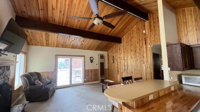 33421 Wild Rose Dr, Green Valley Lake, CA 92341 - carpeted dining room featuring wooden walls, wooden ceiling, ceiling fan, a wainscoted wall, and a stone fireplace