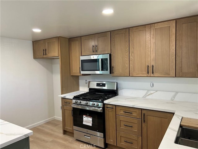 990 244th St, Harbor City, CA 90710 - kitchen with stainless steel appliances, light stone counters, light wood-style flooring, brown cabinets, and recessed lighting