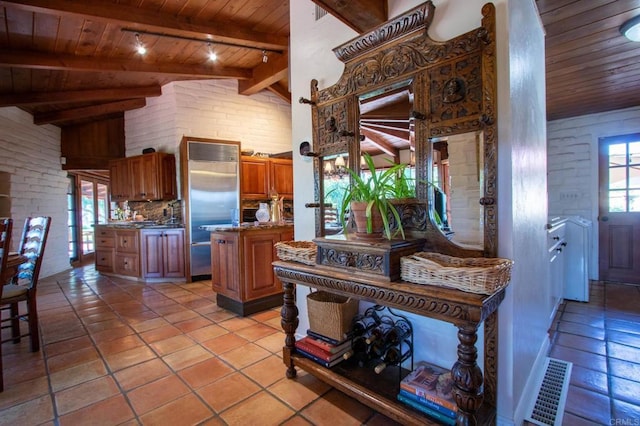 11105 Berry Rd, Valley Center, CA 92082 - kitchen with wood ceiling, brown cabinets, stainless steel built in fridge, light tile patterned floors, and decorative backsplash