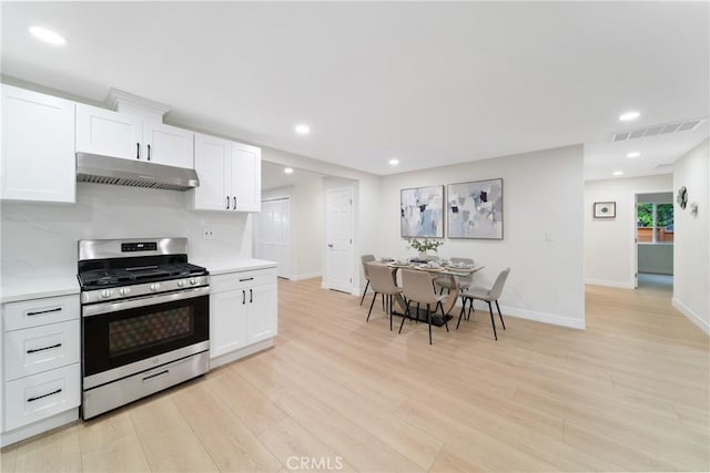 3445 Tilden Ave, Los Angeles, CA 90034 - kitchen with gas stove, under cabinet range hood, light countertops, baseboards, and white cabinets