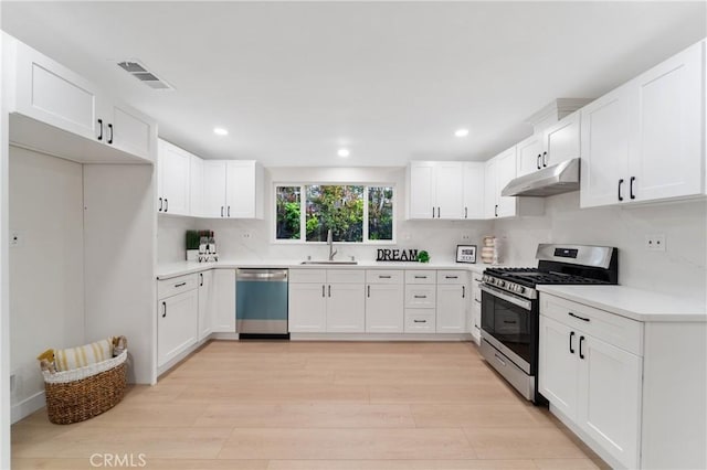 3445 Tilden Ave, Los Angeles, CA 90034 - kitchen featuring stainless steel appliances, under cabinet range hood, a sink, light wood-style flooring, and white cabinetry