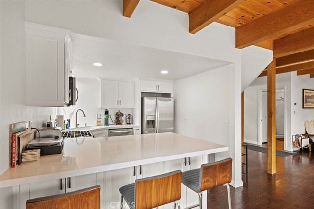 1803 Nob Hill Dr, Running Springs, CA 92382 - kitchen featuring appliances with stainless steel finishes, a peninsula, light countertops, beam ceiling, and dark wood finished floors