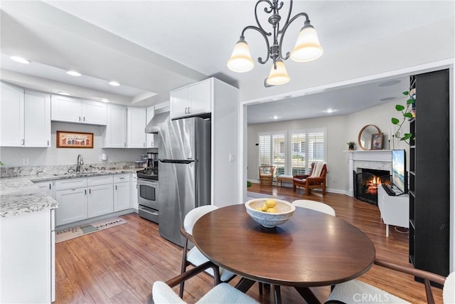 1121 E 1st St, Tustin, CA 92780 - kitchen featuring stainless steel appliances, a sink, white cabinetry, a chandelier, and hanging light fixtures