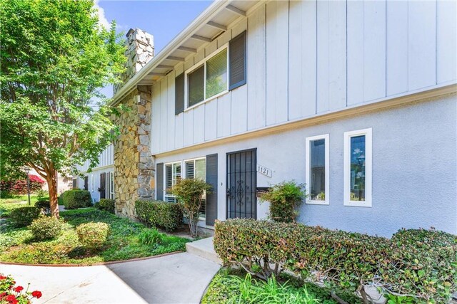 1121 E 1st St, Tustin, CA 92780 - view of front of home with a chimney, stone siding, and board and batten siding