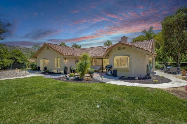 3749 Sarah Ann Dr, Fallbrook, CA 92028 - back of house at dusk with a chimney, stucco siding, a tiled roof, and a patio