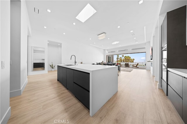 1270 W Chase Dr, Corona, CA 92882 - kitchen featuring modern cabinets, a sink, a skylight, a center island with sink, and light countertops