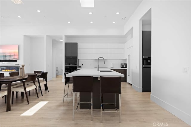 1270 W Chase Dr, Corona, CA 92882 - kitchen featuring a sink, modern cabinets, light countertops, white cabinetry, and a center island with sink