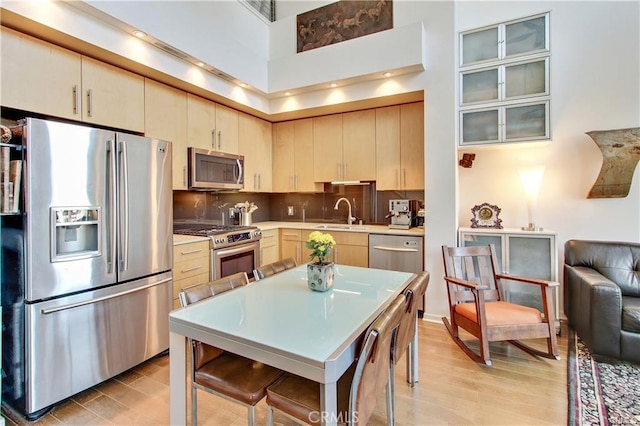 133 The Promenade N Unit 408, Long Beach, CA 90802 - kitchen featuring appliances with stainless steel finishes, a high ceiling, light brown cabinets, light wood-type flooring, and light countertops