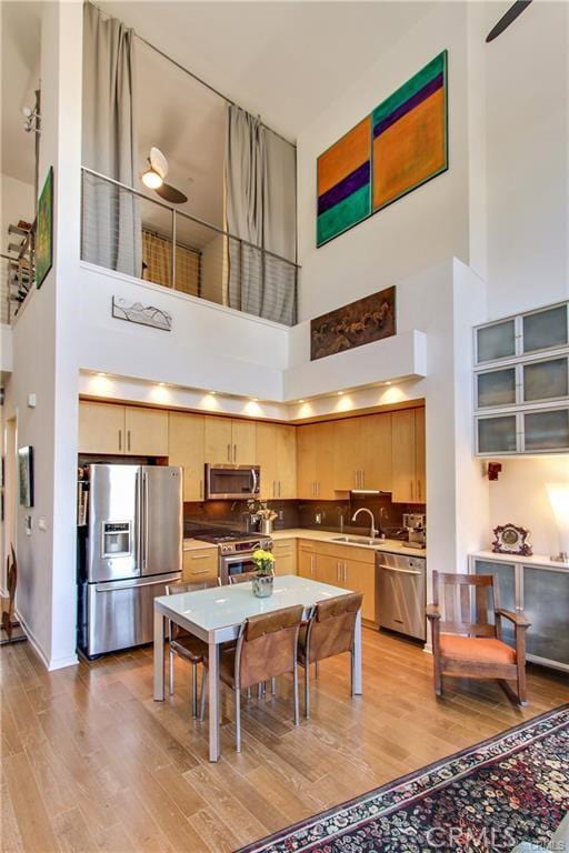 133 The Promenade N Unit 408, Long Beach, CA 90802 - kitchen with appliances with stainless steel finishes, a high ceiling, light wood-style floors, a sink, and light brown cabinets