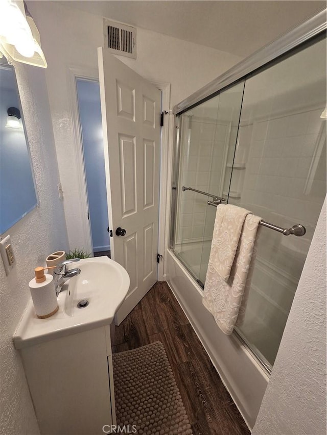 355 Woodlark St, Lancaster, CA 93535 - bathroom featuring wood finished floors, bath / shower combo with glass door, vanity, and a textured wall