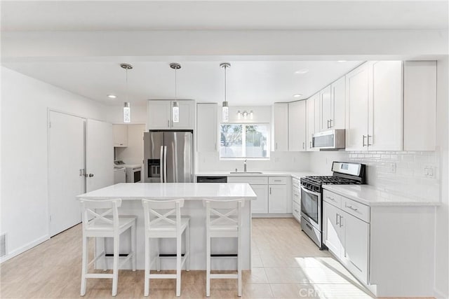 13421 Epping Way, Tustin, CA 92780 - kitchen with appliances with stainless steel finishes, independent washer and dryer, a kitchen bar, a kitchen island, and decorative backsplash