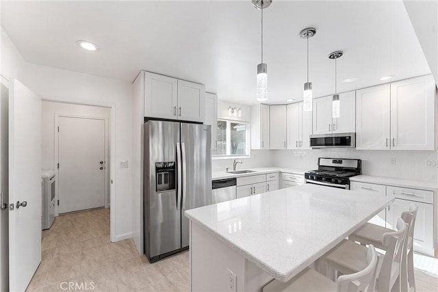 13421 Epping Way, Tustin, CA 92780 - kitchen with appliances with stainless steel finishes, white cabinets, a sink, a breakfast bar area, and a kitchen island