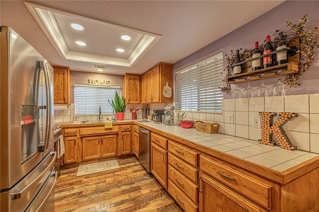 43156 41st St W, Lancaster, CA 93536 - kitchen featuring appliances with stainless steel finishes, a sink, tile countertops, a tray ceiling, and light wood-style floors