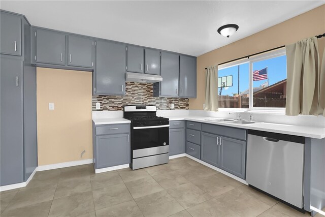 1018 N Millard Ave, Rialto, CA 92376 - kitchen with stainless steel appliances, a sink, under cabinet range hood, gray cabinetry, and tasteful backsplash