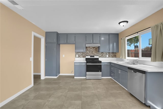 1018 N Millard Ave, Rialto, CA 92376 - kitchen featuring stainless steel appliances, gray cabinets, under cabinet range hood, light countertops, and decorative backsplash