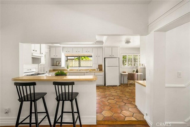 528 E Palmyra Ave, Orange, CA 92866 - kitchen featuring freestanding refrigerator, extractor fan, range with gas stovetop, a peninsula, and a kitchen bar
