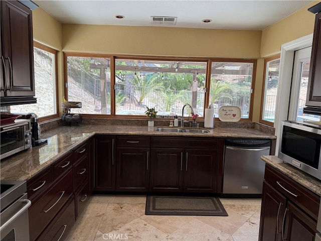 28726 Macklin Ave, Canyon Country, CA 91387 - kitchen with stainless steel appliances, a sink, dark stone counters, and dark brown cabinets