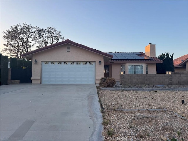 14686 Cool Glen Dr, Helendale, CA 92342 - ranch-style home with stucco siding, driveway, an attached garage, roof mounted solar panels, and a chimney