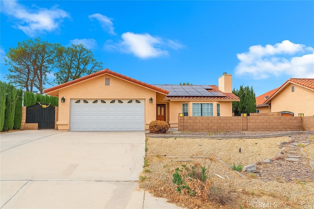 14686 Cool Glen Dr, Helendale, CA 92342 - ranch-style home with stucco siding, driveway, roof mounted solar panels, a garage, and a tile roof