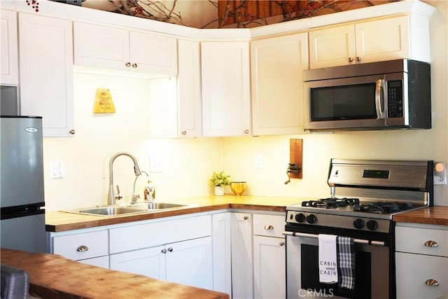 657 Moreno Ln, Sugarloaf, CA 92386 - kitchen with stainless steel appliances, a sink, wooden counters, and white cabinets