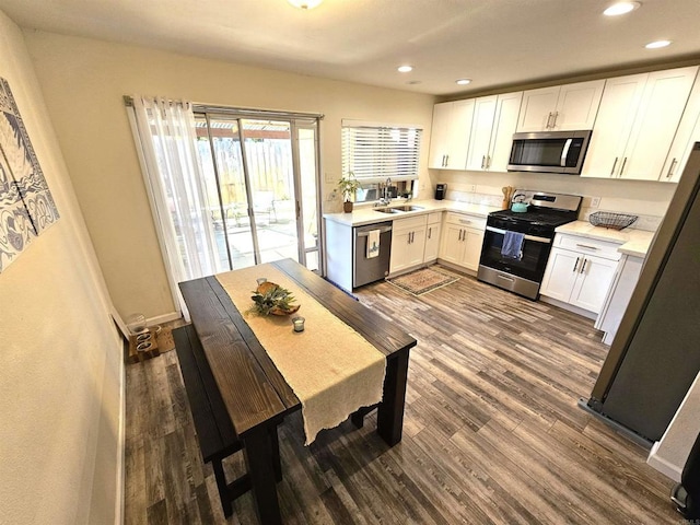 kitchen featuring appliances with stainless steel finishes, a sink, dark wood-type flooring, light countertops, and recessed lighting