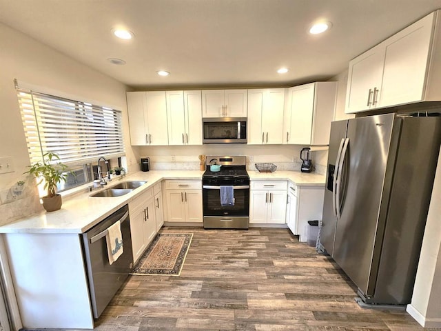 kitchen with stainless steel appliances, a sink, dark wood-type flooring, white cabinetry, and recessed lighting