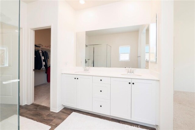 15667 San Diego Ln, Victorville, CA 92394 - bathroom featuring a shower stall, wood finished floors, a walk in closet, double vanity, and baseboards
