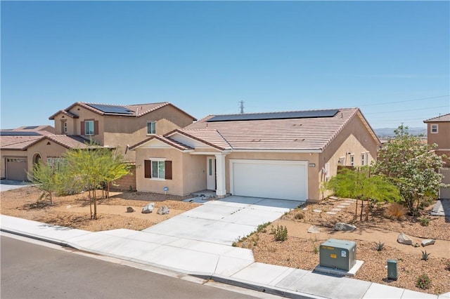 15667 San Diego Ln, Victorville, CA 92394 - view of front of property with a tiled roof, stucco siding, driveway, roof mounted solar panels, and a garage