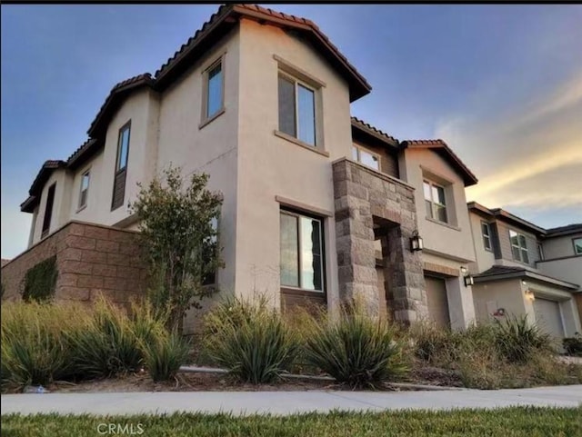 2692 E Penelope Ln, Ontario, CA 91762 - view of home's exterior featuring stucco siding, stone siding, a tile roof, and an attached garage