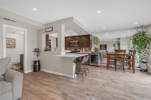 349 S Monte Vista St Unit 20, La Habra, CA 90631 - kitchen with appliances with stainless steel finishes, wine cooler, dark brown cabinets, light countertops, and light wood-style floors