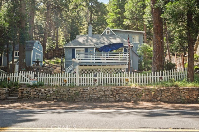 27048 State Highway 189, Blue Jay, CA 92317 - view of front of house featuring a shed, a fenced front yard, a wooden deck, and a chimney