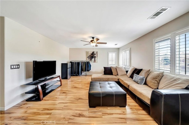 living room featuring light wood-style floors, a ceiling fan, and baseboards