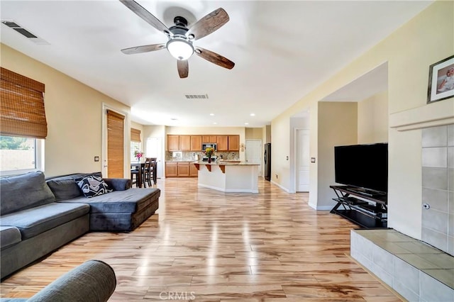 living room with a ceiling fan, light wood-style flooring, healthy amount of natural light, and recessed lighting