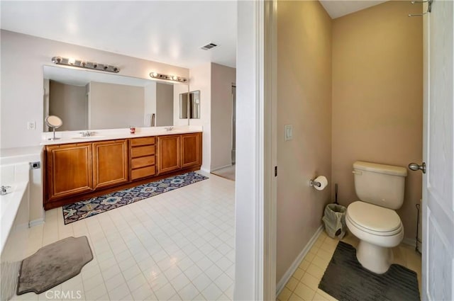bathroom featuring toilet, a bath, double vanity, tile patterned flooring, and baseboards