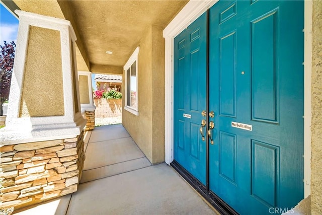 entrance to property featuring stucco siding and a porch