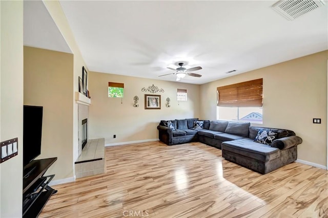 living area featuring healthy amount of natural light, light wood finished floors, and a tiled fireplace