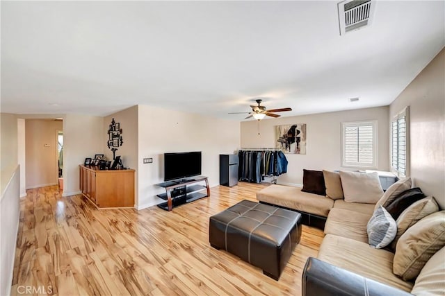 living room featuring ceiling fan, light wood finished floors, and plenty of natural light