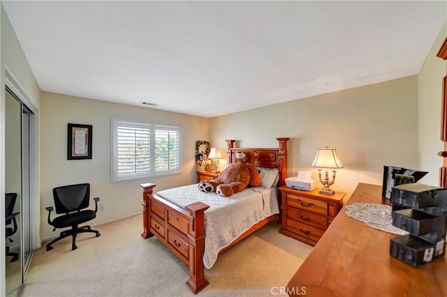 bedroom with a closet, light carpet, and an office area
