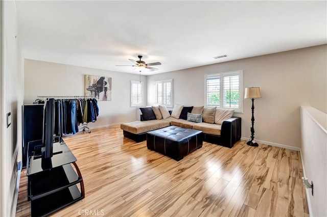 living room with a ceiling fan, light wood-style flooring, and baseboards